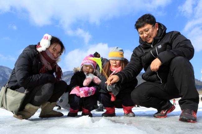 인제 빙어호에 마련된 빙어 축제 행사장에서 한 가족이 얼음을 뚫고 빙어낚시를 하고 있다. 