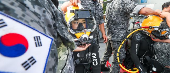 ▲ 이 홍보위원이 표면공급잠수체계 체험을 위해 14㎏에 달하는 헬멧을 착용하고 있다. 이 홍보위원이 착용한 잠수장비는 총 30㎏에 육박한다. 
