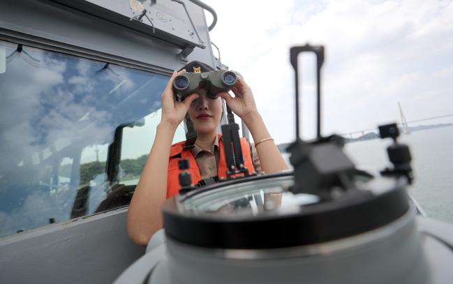 임 홍보위원이 광주함 함교 밖에서 쌍안경으로 해상 목표물을 확인하고 있다.